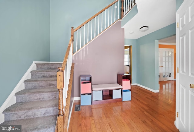 stairway with baseboards, a high ceiling, and wood finished floors