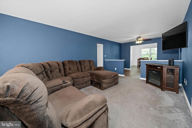 carpeted living room featuring baseboards and ceiling fan