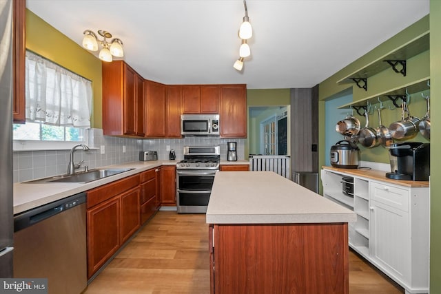 kitchen with a sink, appliances with stainless steel finishes, backsplash, and light countertops