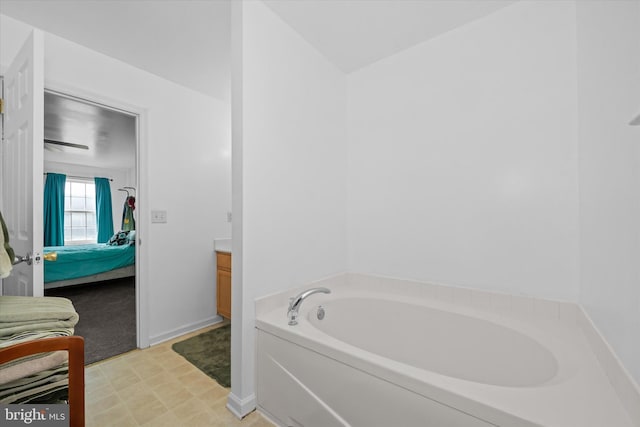 bathroom featuring ensuite bathroom, baseboards, a garden tub, and vanity