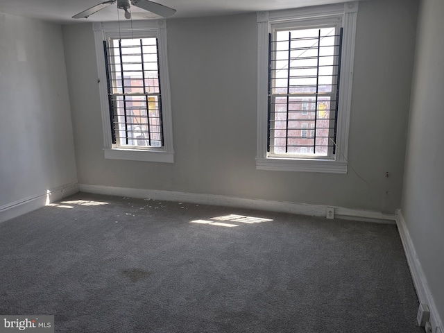 carpeted spare room featuring baseboards and a ceiling fan