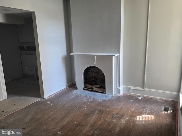 unfurnished living room featuring visible vents, a fireplace with flush hearth, and wood finished floors