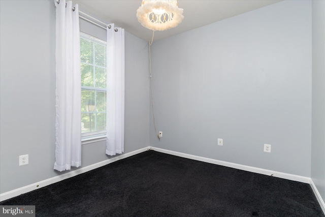 empty room featuring baseboards, dark carpet, and a chandelier