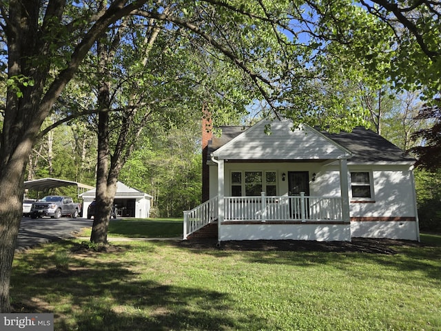 view of front of property with a carport, a chimney, a porch, and a front yard