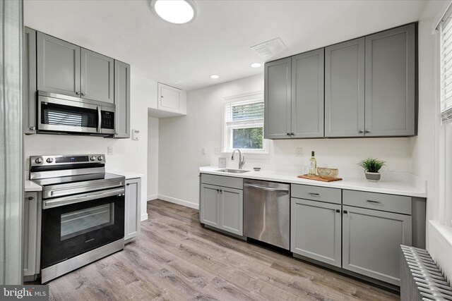 kitchen with a sink, appliances with stainless steel finishes, gray cabinetry, and recessed lighting