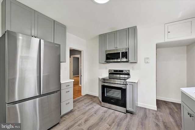 kitchen with light wood-style floors, gray cabinetry, and stainless steel appliances