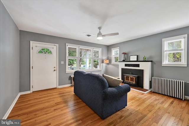 living area with baseboards, plenty of natural light, radiator heating unit, and light wood-style flooring