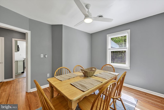 dining room with a ceiling fan, baseboards, visible vents, and light wood finished floors