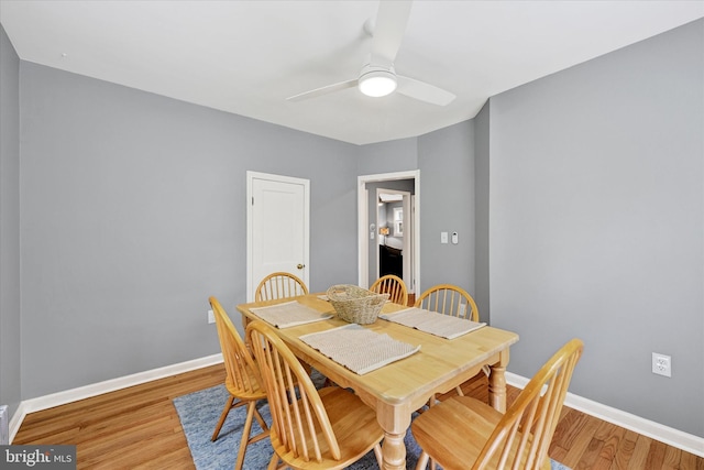 dining room with baseboards, a ceiling fan, and light wood-style flooring