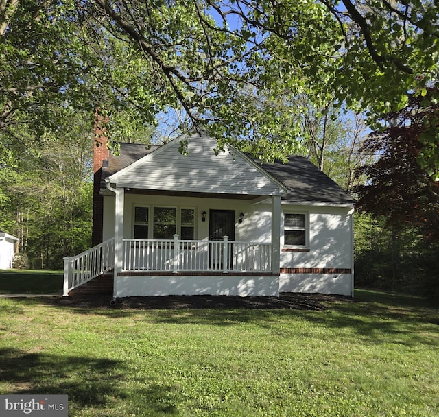bungalow featuring a chimney, a porch, and a front lawn