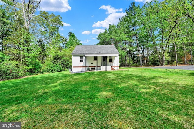 rear view of property featuring a yard and a porch