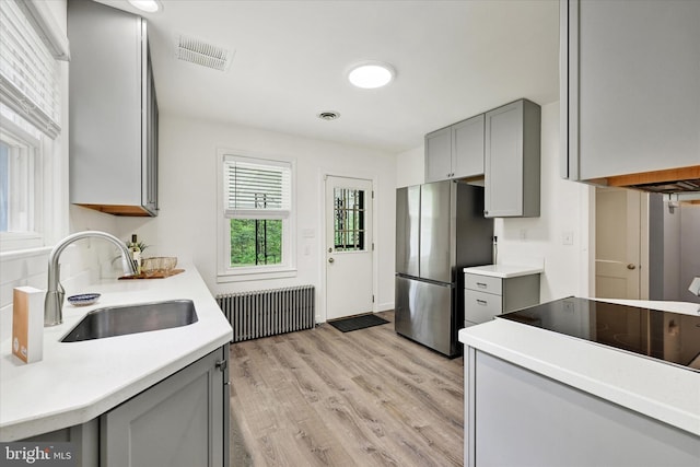 kitchen with gray cabinets, visible vents, a sink, freestanding refrigerator, and radiator