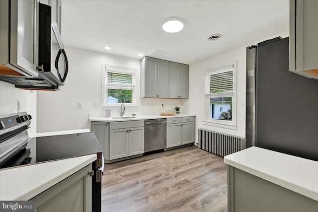 kitchen featuring a sink, appliances with stainless steel finishes, gray cabinets, and radiator heating unit