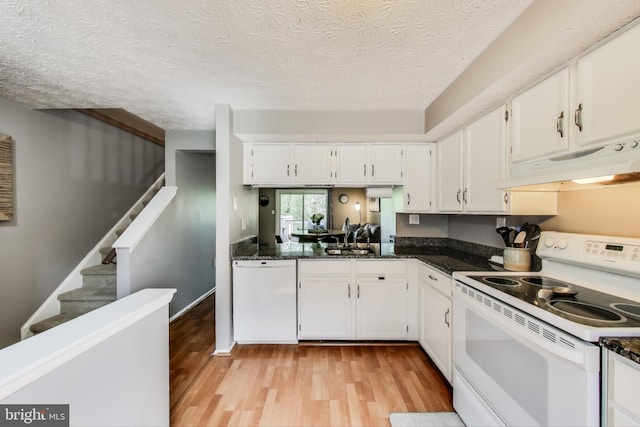 kitchen featuring white appliances, light wood-style floors, under cabinet range hood, white cabinets, and a sink