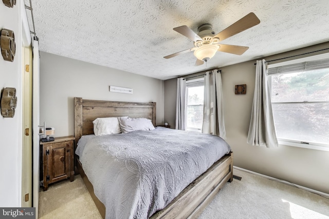 bedroom featuring light colored carpet, a textured ceiling, and ceiling fan