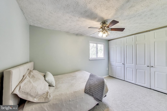 bedroom featuring carpet floors, a ceiling fan, a textured ceiling, and a closet