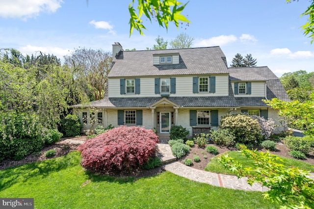 country-style home featuring a chimney and a front yard