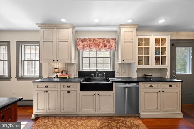 kitchen with cream cabinets, dark countertops, a sink, dishwasher, and light wood-type flooring