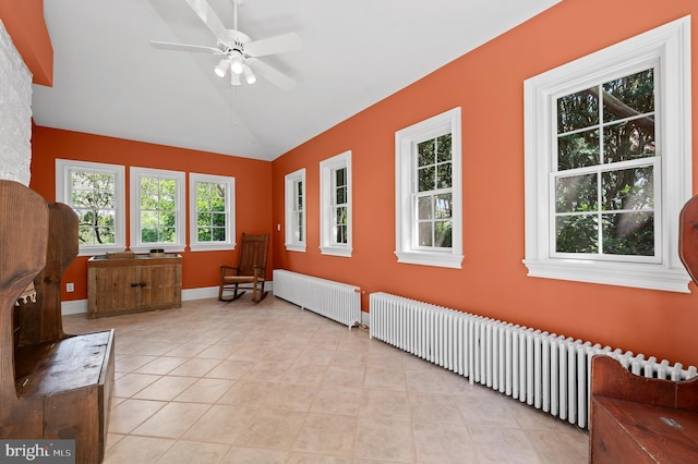 interior space featuring lofted ceiling, radiator heating unit, light tile patterned flooring, and ceiling fan
