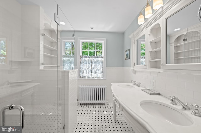 full bath with a sink, radiator, tile walls, and a wealth of natural light