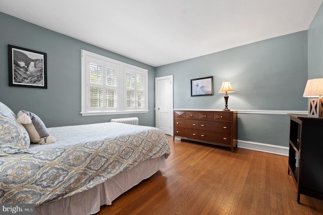bedroom featuring radiator, baseboards, a closet, and wood finished floors