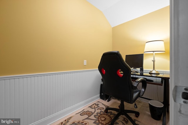 office with lofted ceiling and a wainscoted wall