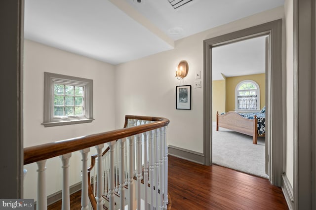 hallway featuring baseboards, dark wood-style flooring, and an upstairs landing