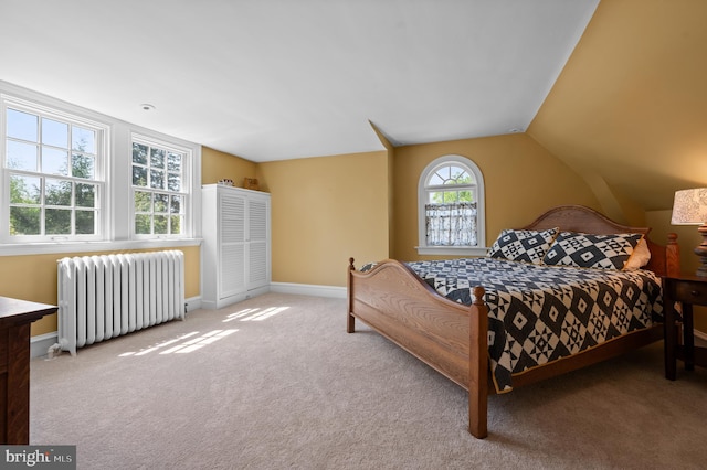 carpeted bedroom with radiator heating unit, baseboards, and vaulted ceiling