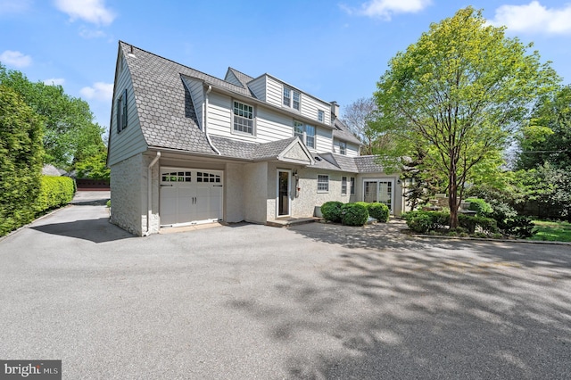 shingle-style home featuring a garage and driveway