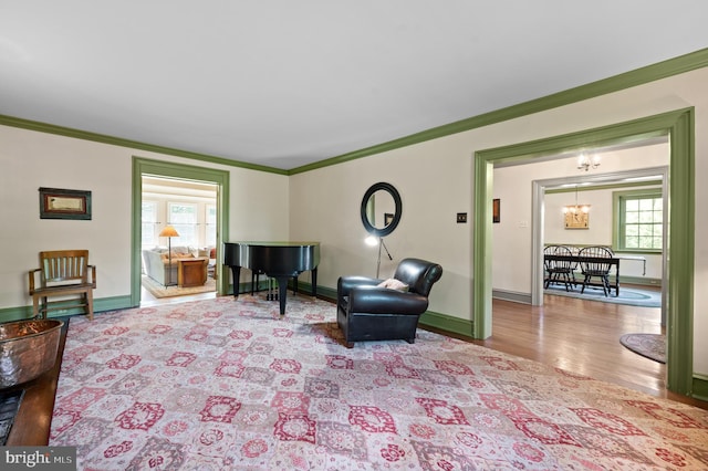 sitting room featuring baseboards, ornamental molding, wood finished floors, and a notable chandelier