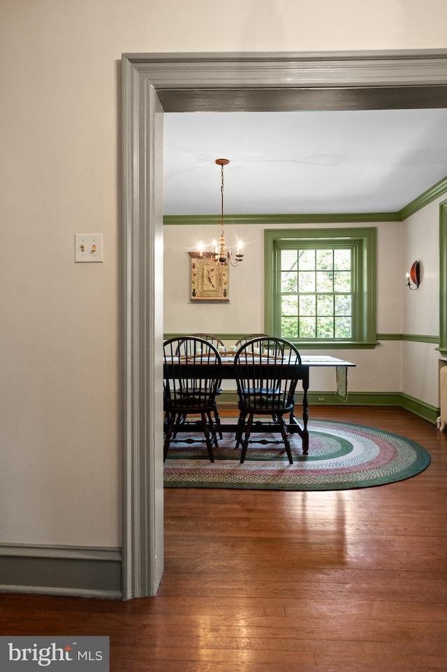 dining area featuring crown molding, a notable chandelier, and hardwood / wood-style floors