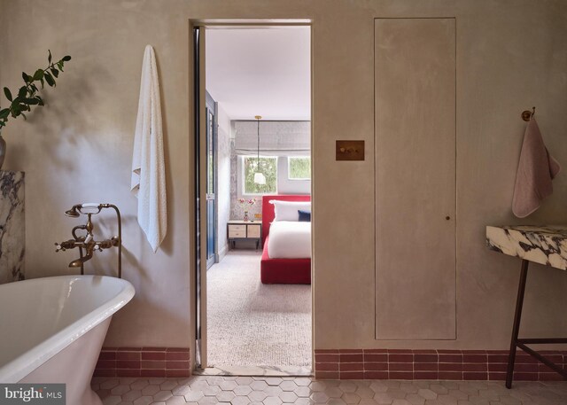ensuite bathroom featuring connected bathroom, a soaking tub, and tile patterned flooring