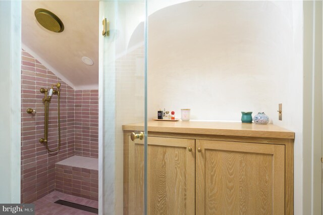full bath featuring vaulted ceiling and a tile shower