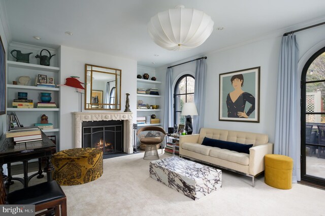 living area with built in features, ornamental molding, and a warm lit fireplace