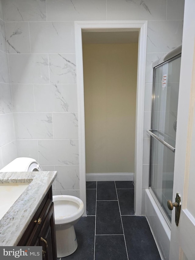 full bathroom with tile walls, tile patterned flooring, vanity, toilet, and enclosed tub / shower combo