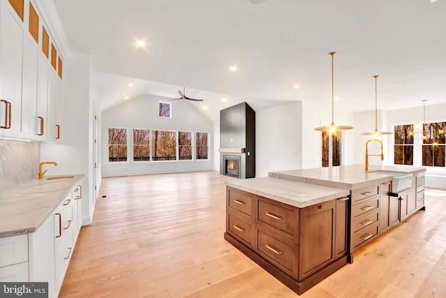 457 Brownsburg Rd W, Unit W, Newtown, PA 18940 - kitchen featuring brown cabinetry, a large island, light stone countertops, a sink, and white cabinetry