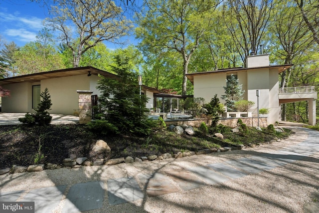 view of side of home with a carport, stucco siding, and a chimney