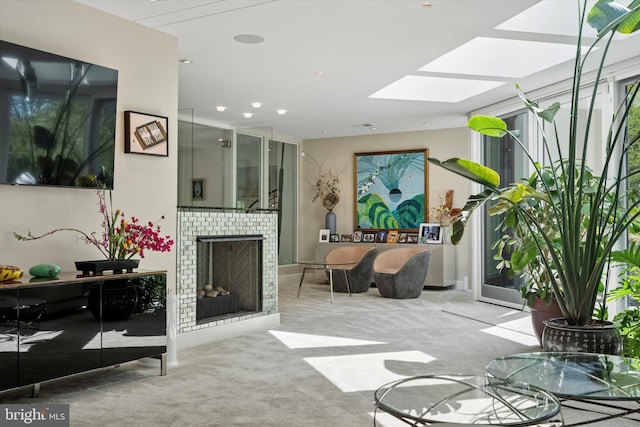 carpeted living room featuring a skylight, a fireplace, and recessed lighting
