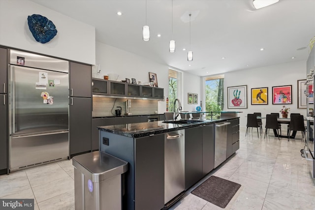 kitchen with decorative backsplash, a center island with sink, recessed lighting, a sink, and stainless steel appliances
