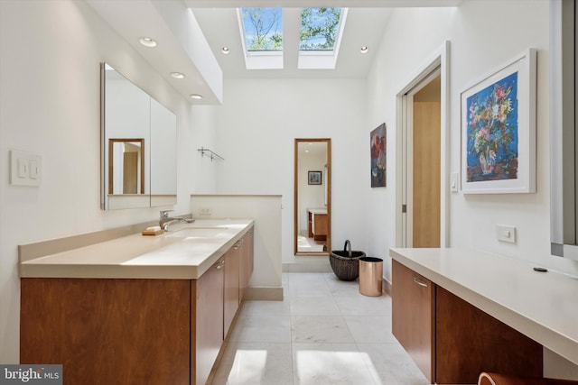 bathroom with a skylight, tile patterned flooring, vanity, baseboards, and recessed lighting