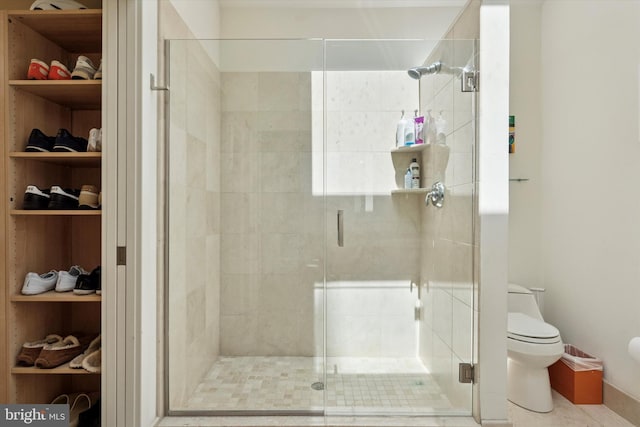 bathroom featuring toilet, a shower stall, and a walk in closet