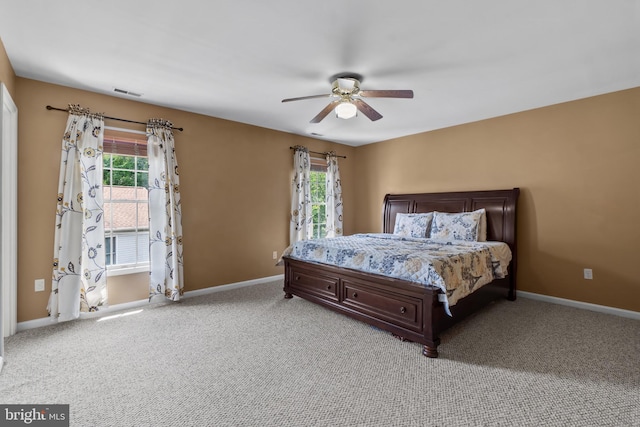 bedroom with multiple windows, light colored carpet, and baseboards
