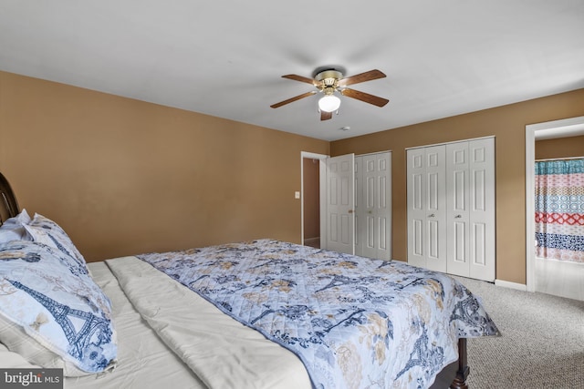 carpeted bedroom with two closets, ceiling fan, and baseboards