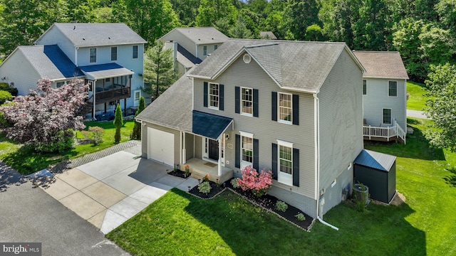 colonial-style house with concrete driveway, an attached garage, a front lawn, and a porch