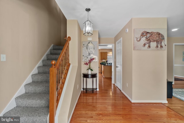 foyer entrance with light wood-type flooring, stairs, and baseboards