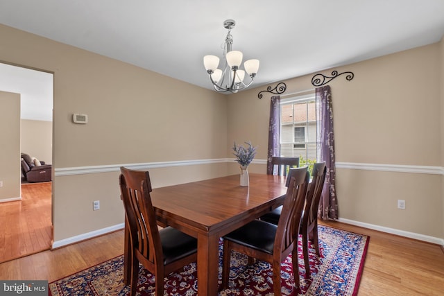 dining room featuring a chandelier, wood finished floors, and baseboards