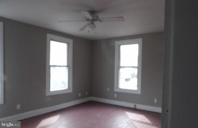 spare room with baseboards, a ceiling fan, and a healthy amount of sunlight