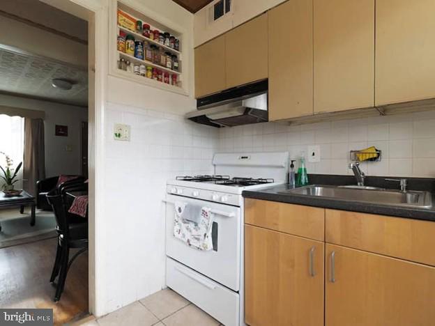 4627 Central Ave NE, Washington, DC 20019 - kitchen featuring dark countertops, a sink, gas range gas stove, under cabinet range hood, and visible vents