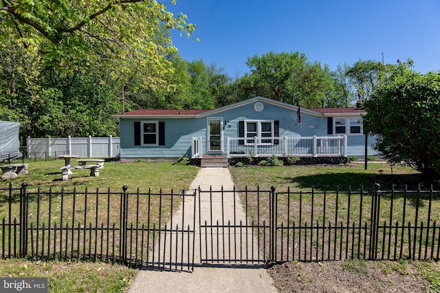 manufactured / mobile home with a wooden deck, a fenced front yard, and a front lawn