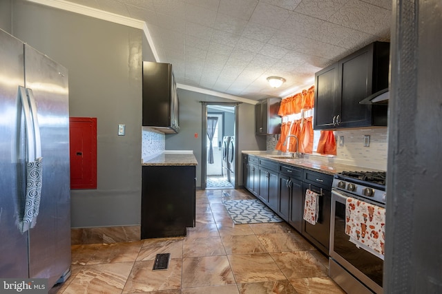kitchen featuring crown molding, decorative backsplash, washing machine and dryer, a sink, and stainless steel appliances
